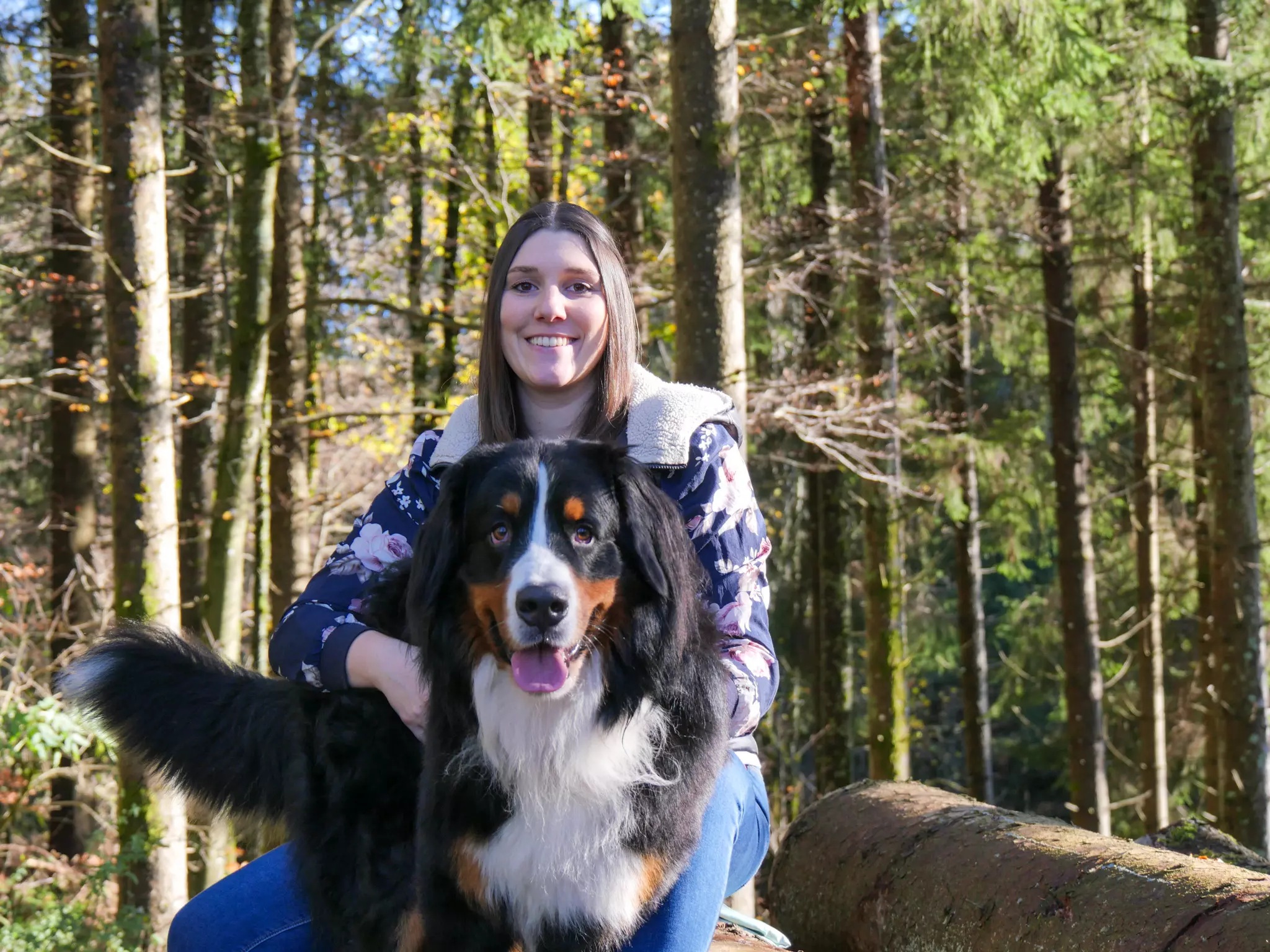 Hundetrainerin Nadja Amann mit ihrem Berner Sennenhund Buddy sitzt auf einem Baumstamm
